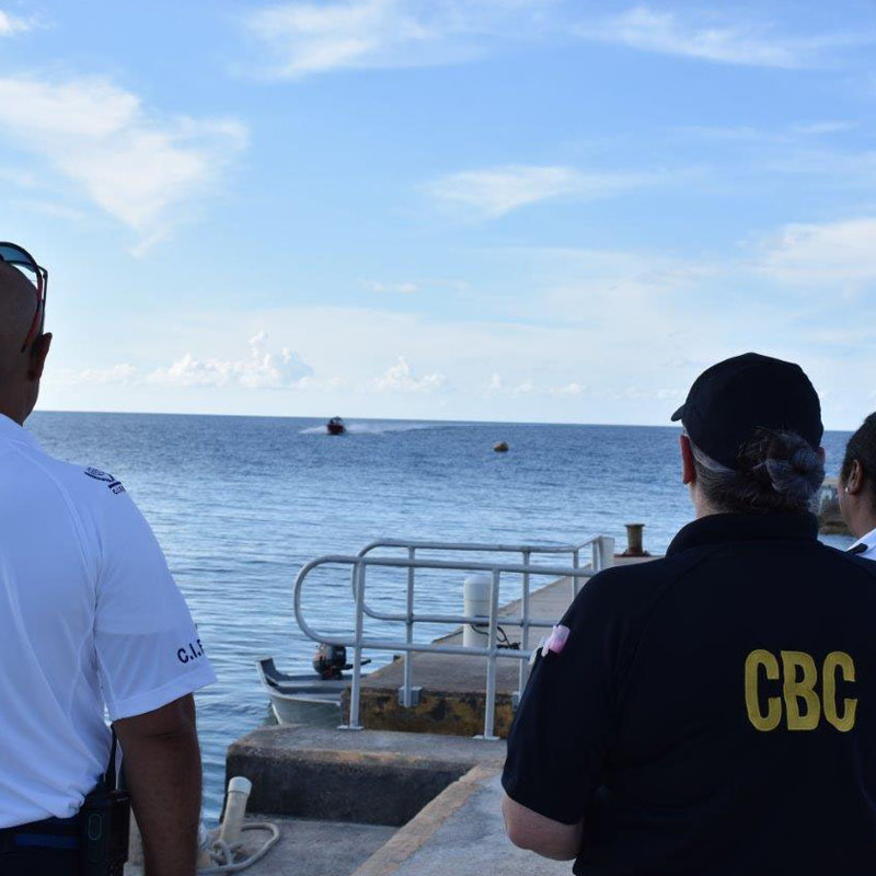 Three officers looking out at a speedboat in the ocean